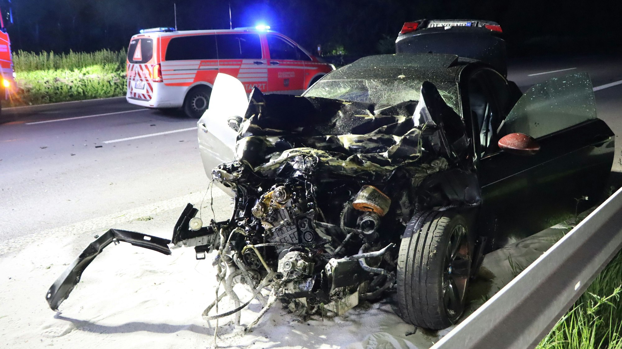 Zwei völlig zerstörte Autos liegen auf der Autobahn 555, ein Rettungsfahrzeug steht daneben.