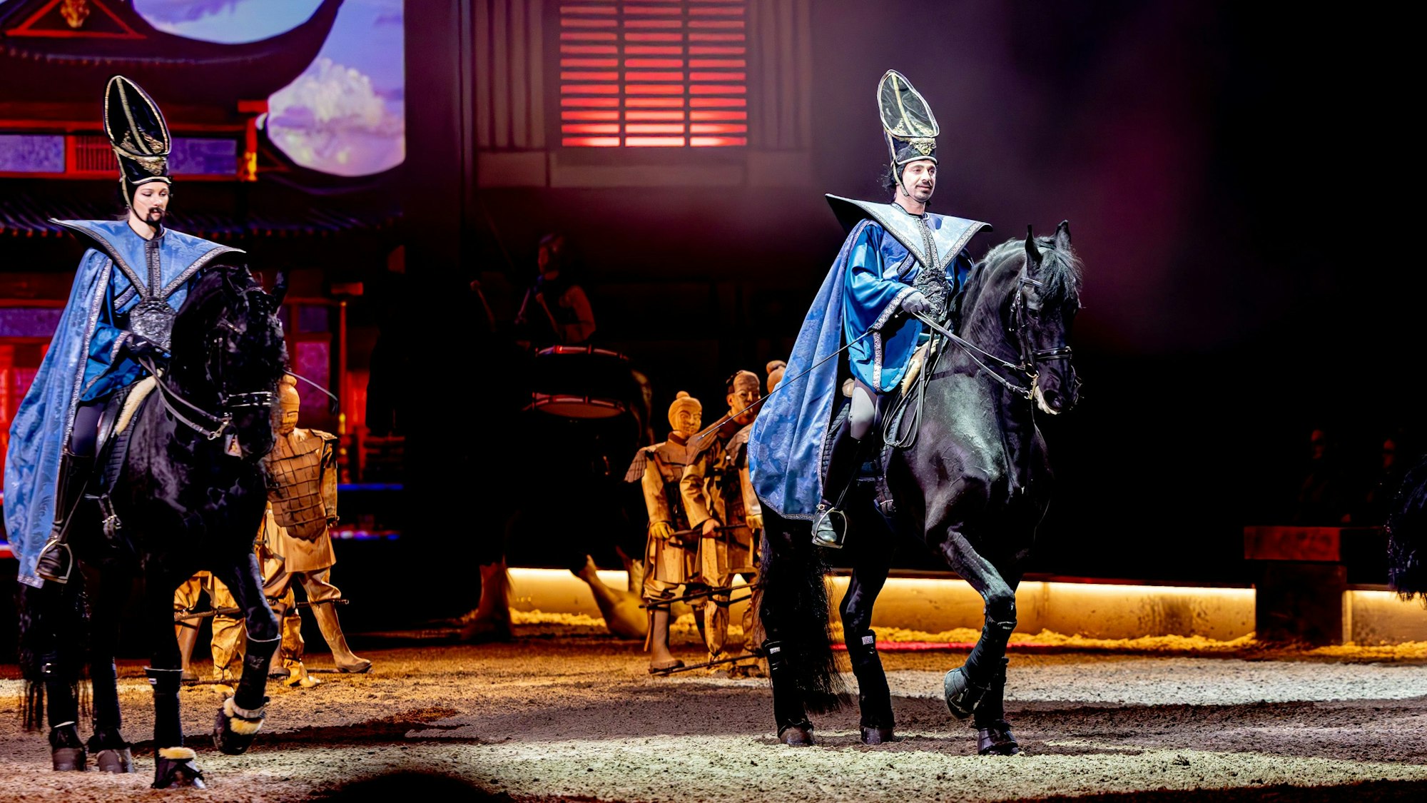 Zwei Reiter sitzen auf schwarzen Pferden.