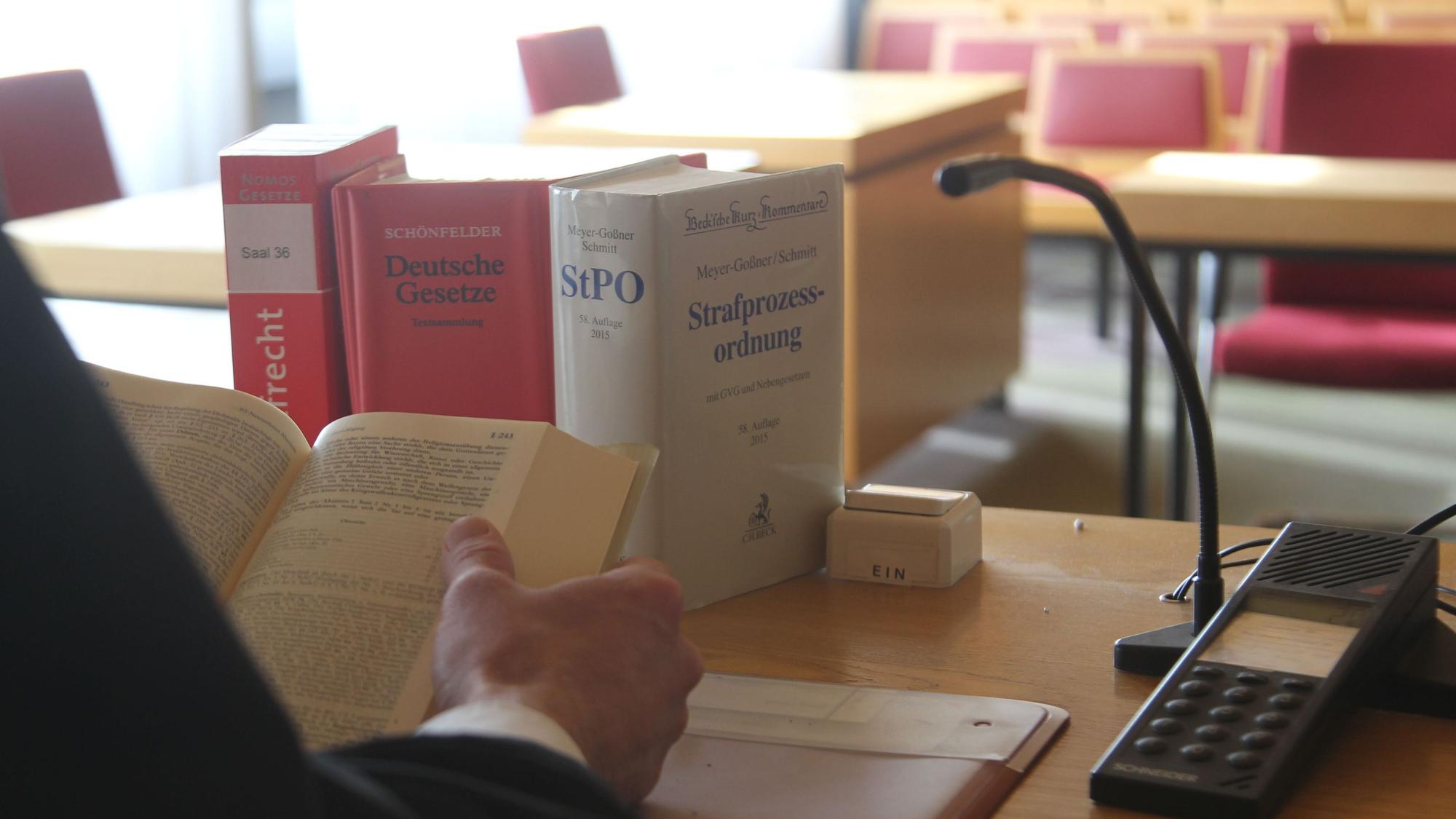 Gesetzesbücher neben einem Mikrofon in einem Gerichtssaal.