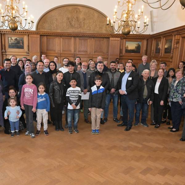 Hintereinander stehen die Gäste sowie Vertreter von Stadtverwaltung und Integrationsrat in Viererreihen.
