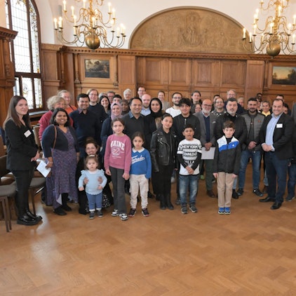 Hintereinander stehen die Gäste sowie Vertreter von Stadtverwaltung und Integrationsrat in Viererreihen.