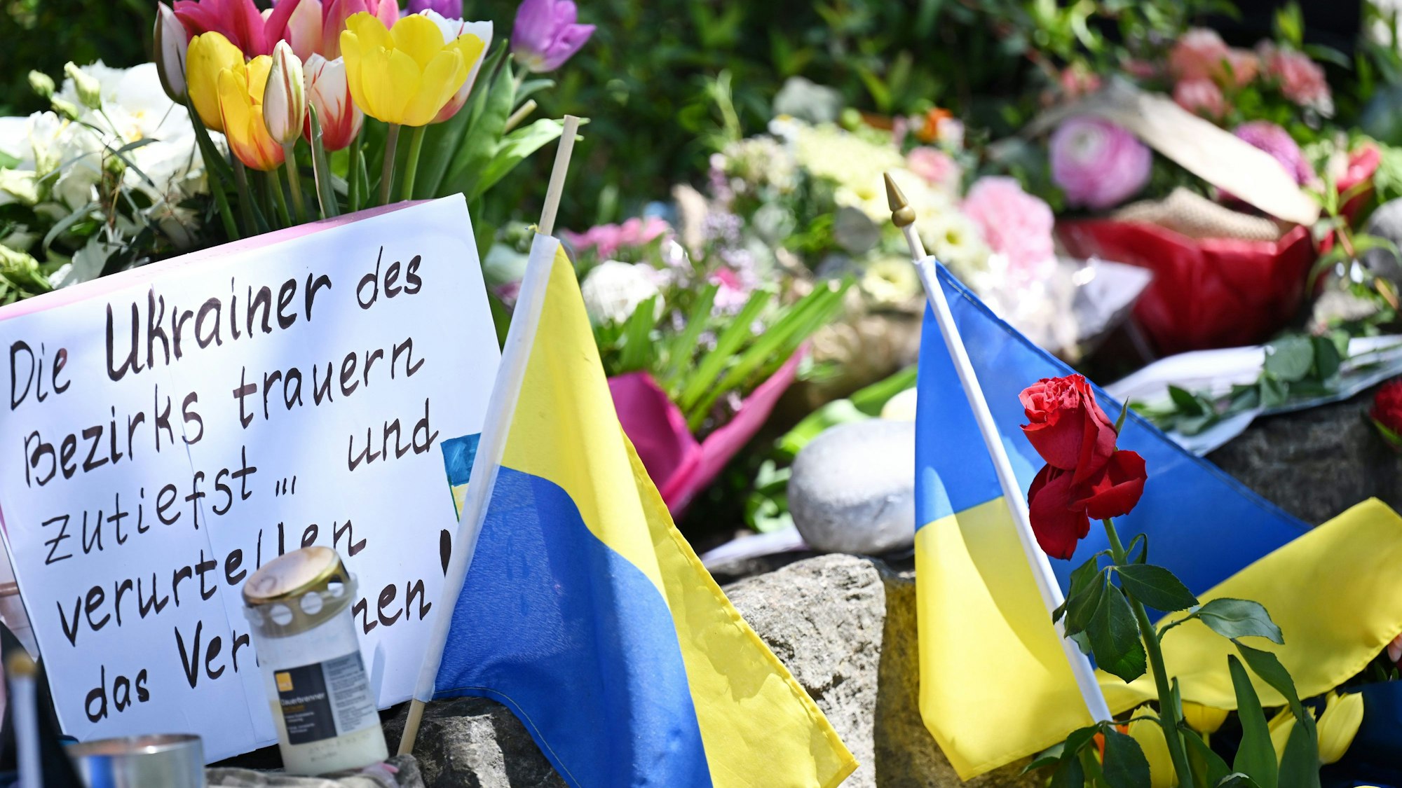 Neben dem Einkaufszentrum an dem am Samstagabend zwei Männer aus der Ukraine getötet worden sind, haben Menschen Blumen und Plakate niedergelegt. Die beiden getötete Ukrainer waren Armeeangehörige.