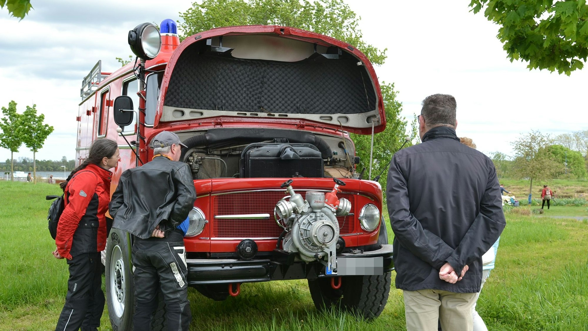 Ein Paar schaut in den Motorraum eines alten Feuerwehrautos.