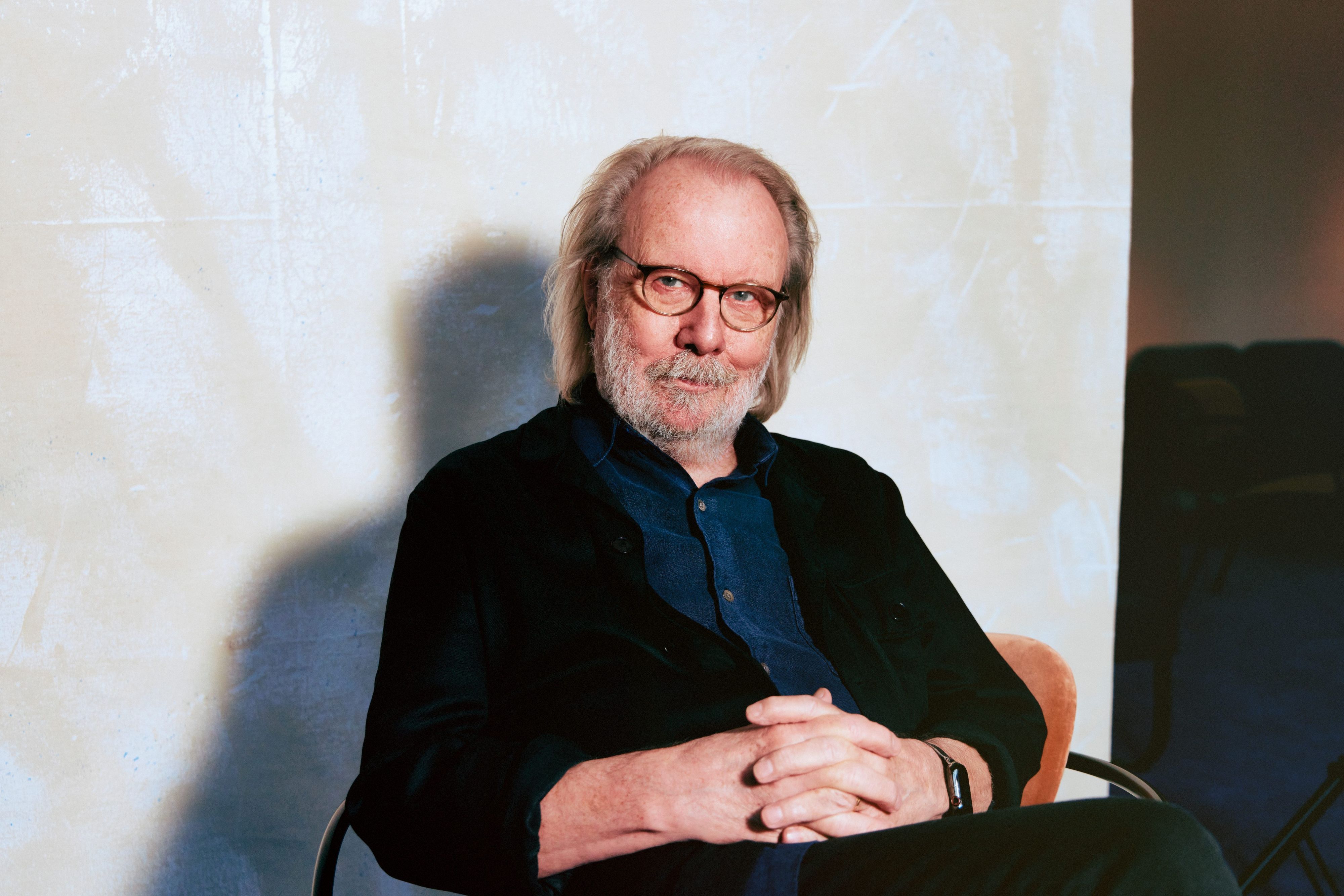 Abba-Star Benny Andersson sitzt auf einem Stuhl und sieht in die Kamera.