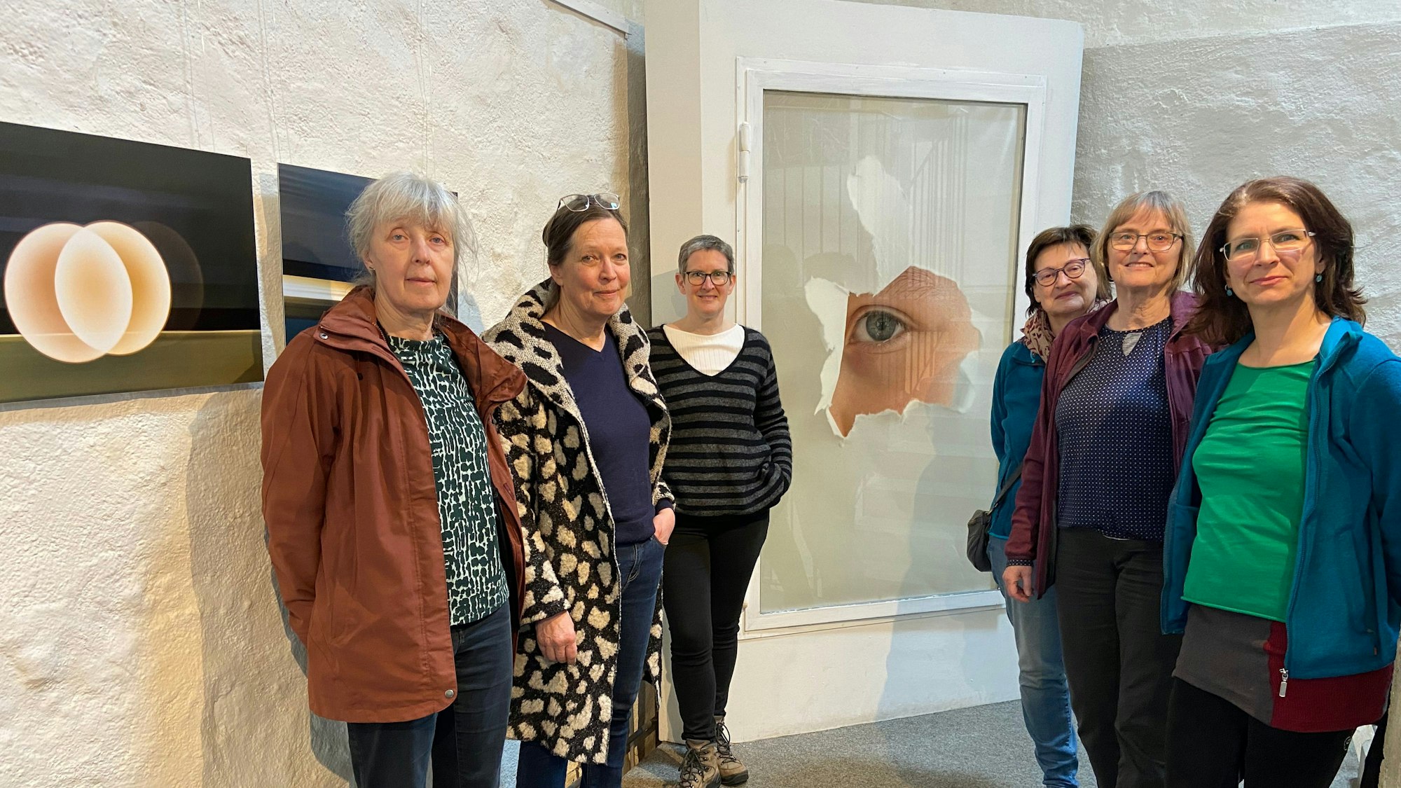 Sechs Künstlerinnen aus Kassel stehen im Zündorfer Wehrturm vor Werken ihrer gemeinsamen Ausstellung. Foto von Beatrix Lampe