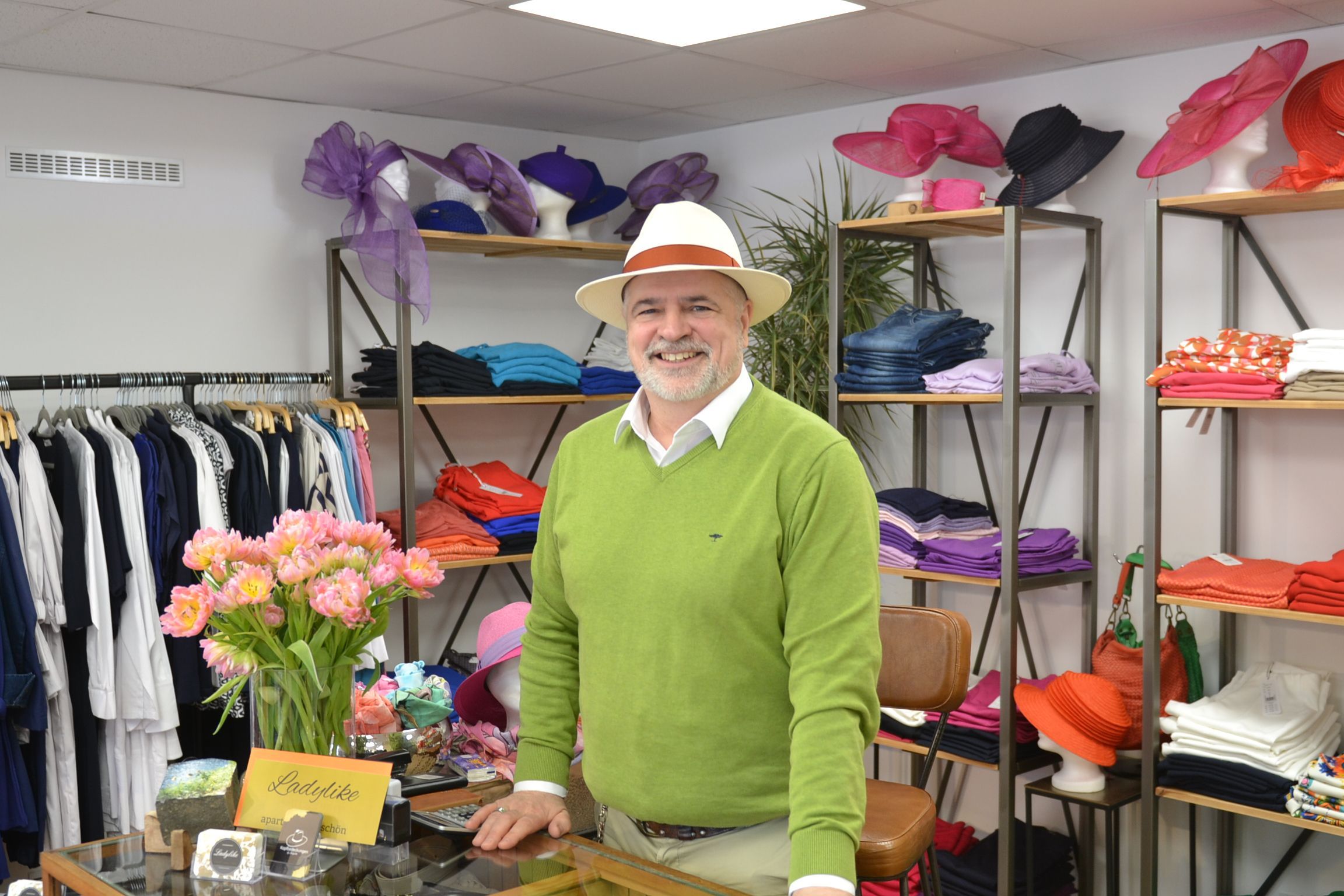 Norbert Hollender steht zwischen Regalen mit Hüten und Kleidung.