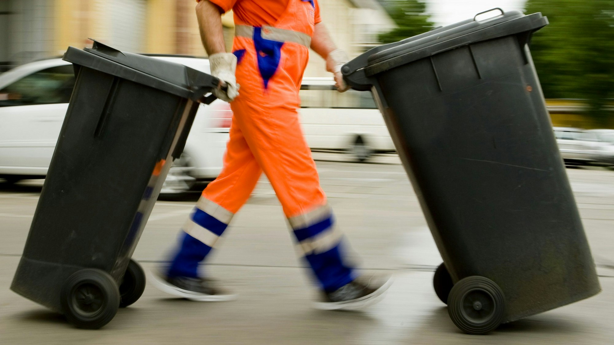 Ein Müllmann schiebt Mülltonnen (Archivbild)