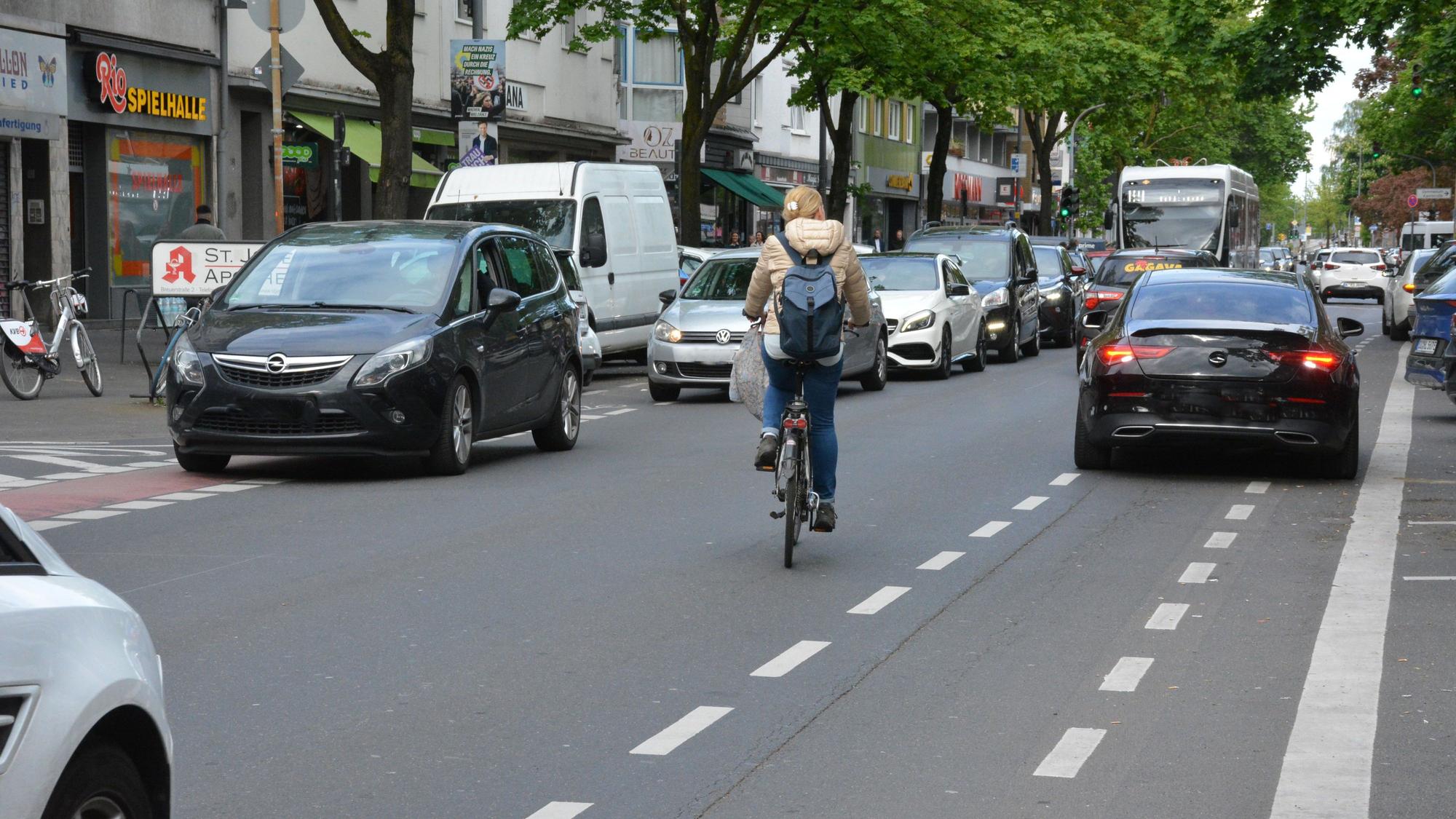 Radfahrerin weicht Autos aus, das auf der Kalker Hauptstraße auf dem Radweg parkt.