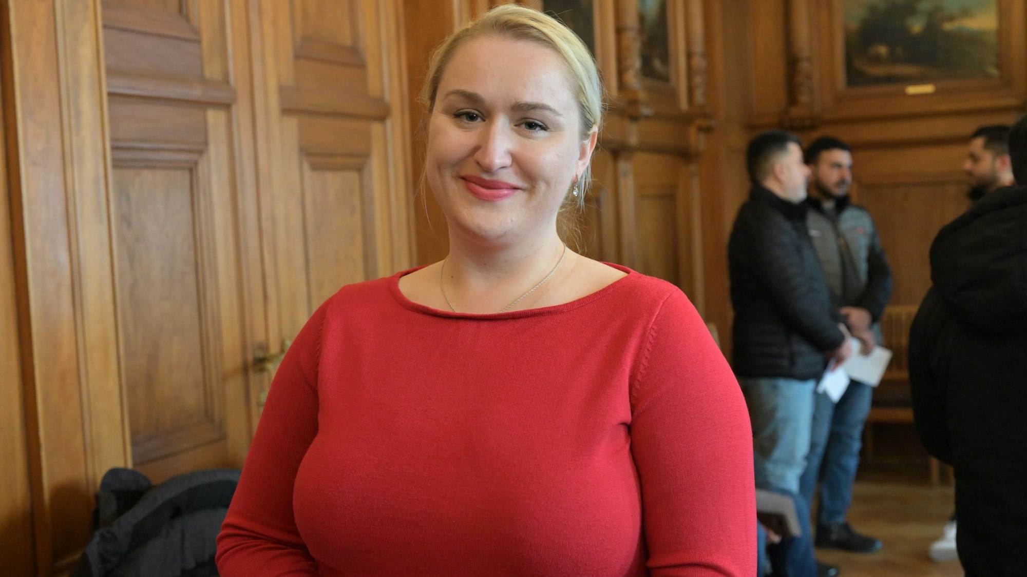 Porträtfoto der blondhaarigen Frau mit rotem Pullover.