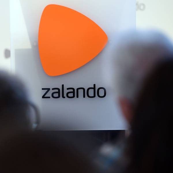 Das Logo des Onlineversandhändlers Zalando ist an einer Glasfassade zu sehen. Markant ist über dem Schriftzug ein orangefarbenes Dreieck zu erkennen.