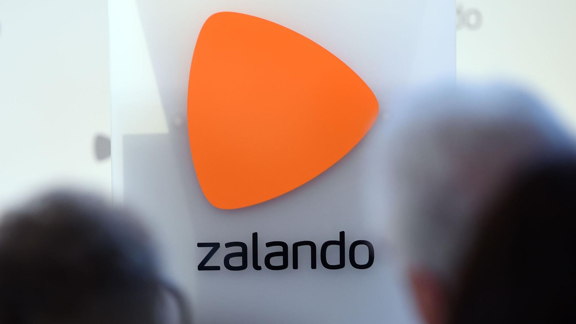 Das Logo des Onlineversandhändlers Zalando ist an einer Glasfassade zu sehen. Markant ist über dem Schriftzug ein orangefarbenes Dreieck zu erkennen.