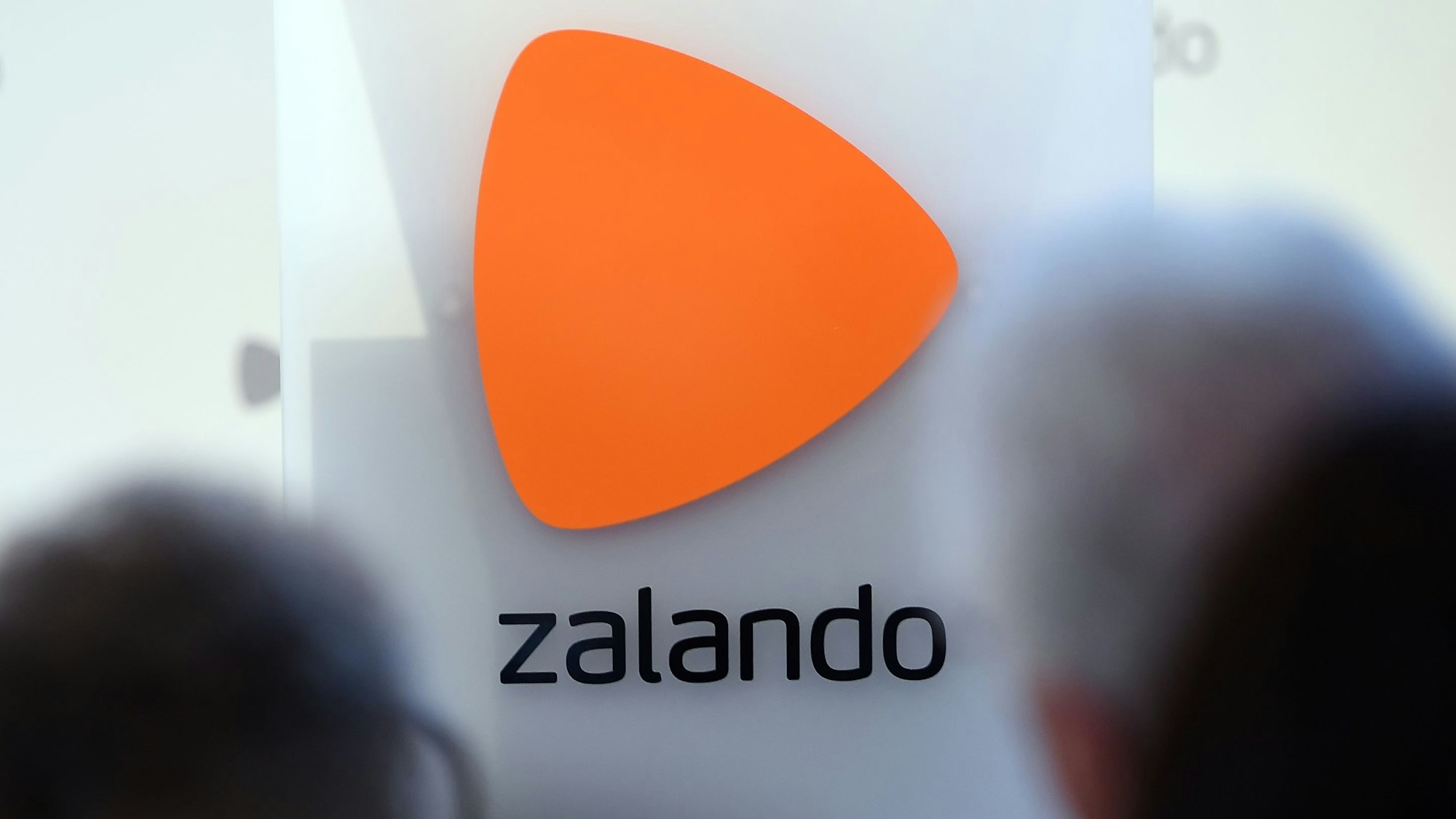 Das Logo des Onlineversandhändlers Zalando ist an einer Glasfassade zu sehen. Markant ist über dem Schriftzug ein orangefarbenes Dreieck zu erkennen.