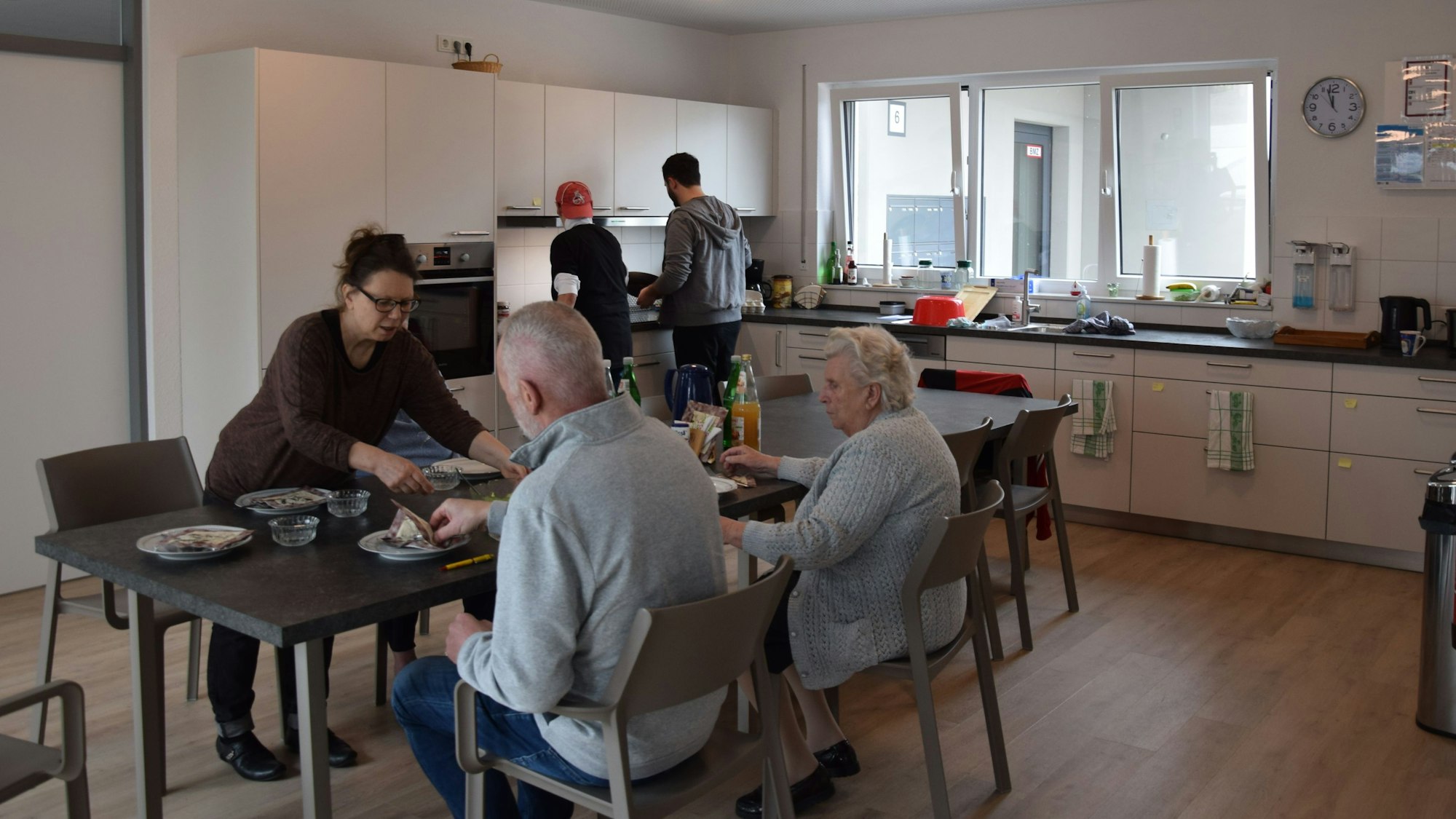 Zu sehen mehrere Menschen in einer Küche.