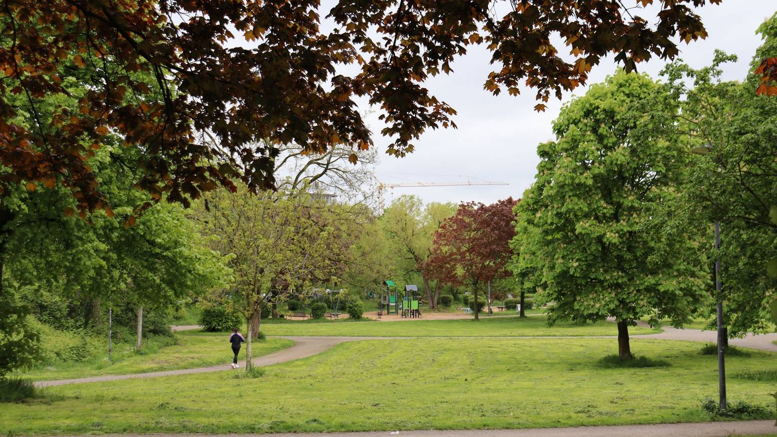 Blick auf den Böckingpark in Köln-Mülheim. Grüne Wiesen und Bäume sowie eine Joggerin und ein Spielplatz sind zu sehen. Foto von Uwe Schäfer
