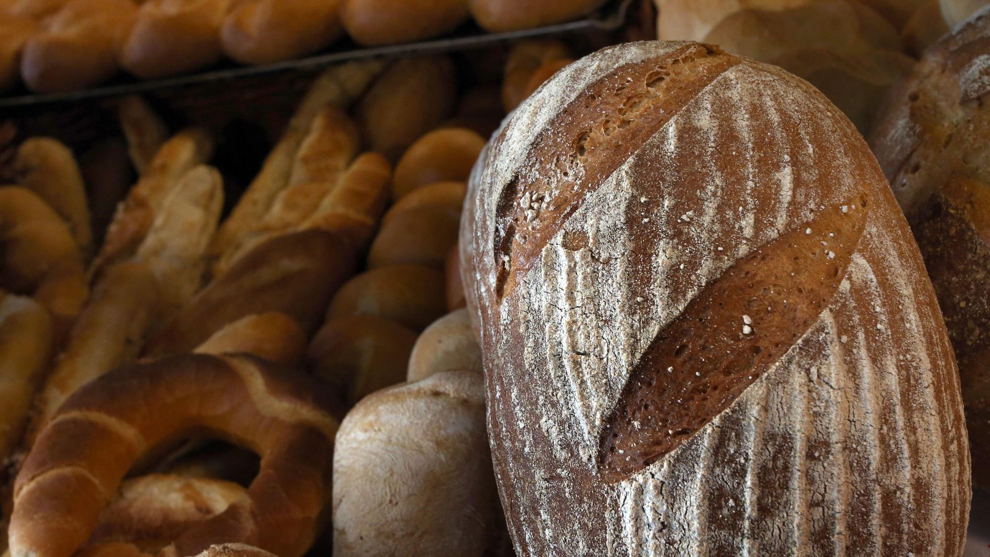 Ein Brot, Brötchen und Hörnchen liegen in der Auslage eines Bäckers.