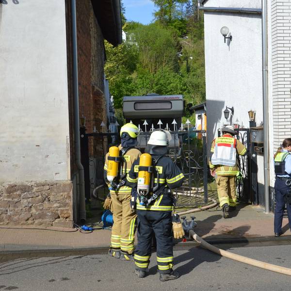Feuerwehrleute und zwei Polizistinnen stehen vor dem Haus in der Hauserbachstraße.
