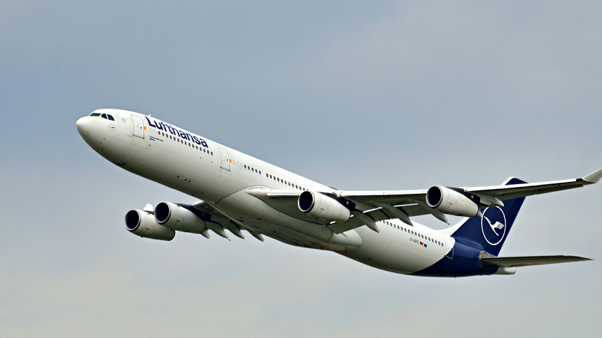Ein Airbus A340 der deutschen Fluggesellschaft Lufthansa startet inmitten grauer Wolken. Das Flugzeug ist markant in weiß und blau lackiert. (Symbolbild)