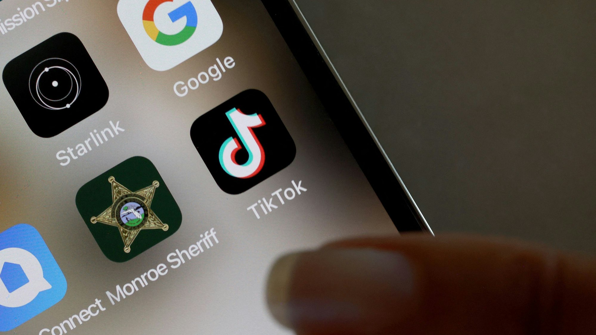 Ein Finger zeigt auf ein TikTok-Icon auf einem Handy.
