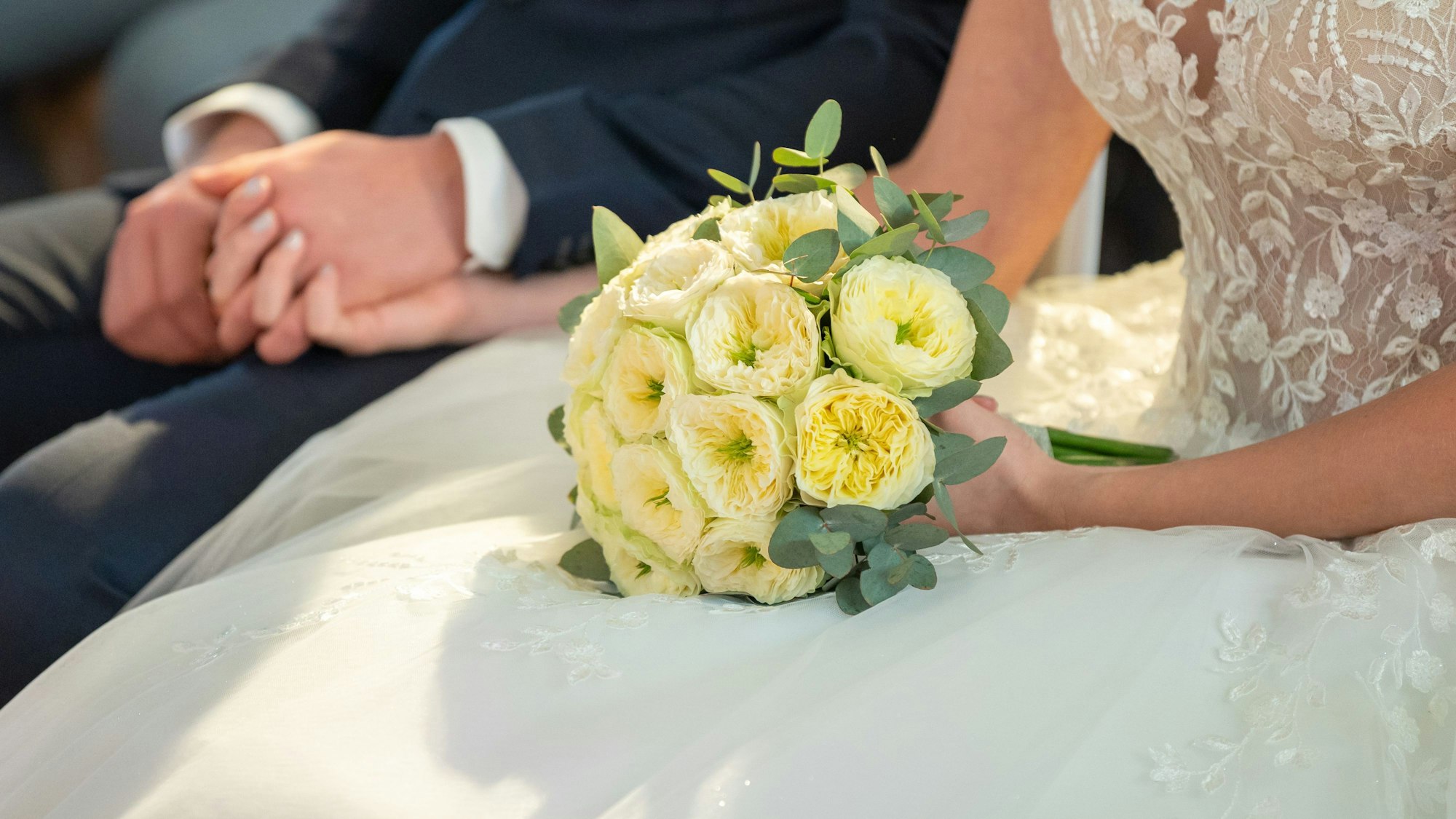 Ein Brautpaar hält sich während ihrer Trauung die Hände.