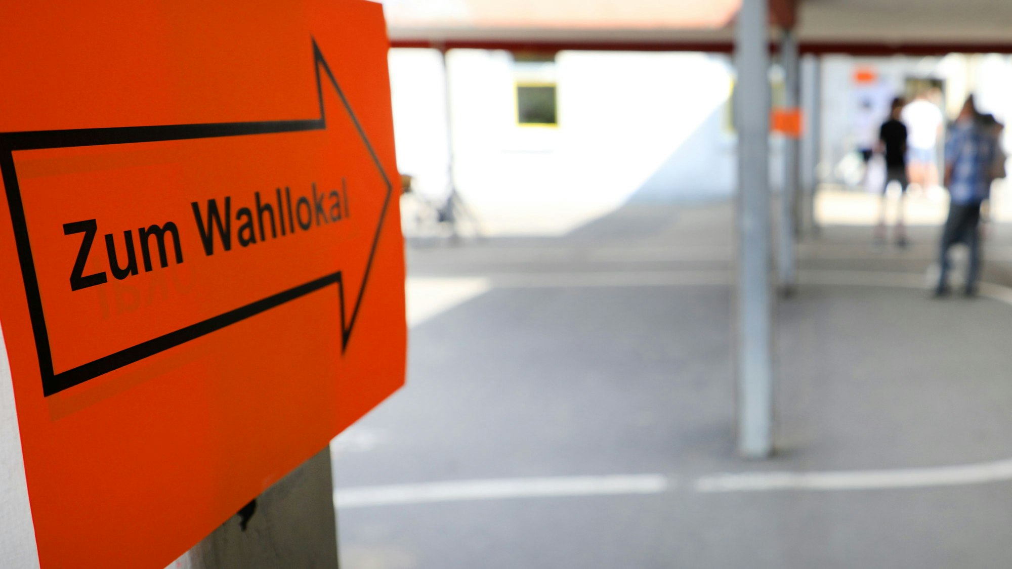 Eingang zu einem Wahllokal. Ein rotes Schild mit einem Pfeil darauf weist in die Richtung.