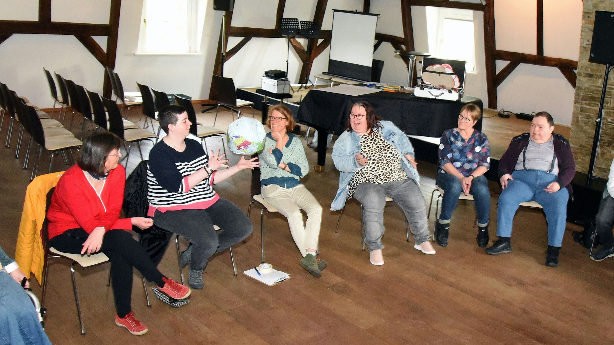 Menschen sitzen in einem Stuhlkreis im Wiehler Burghaus, eine Weltkugel aus Pappmachee wird herumgereicht.