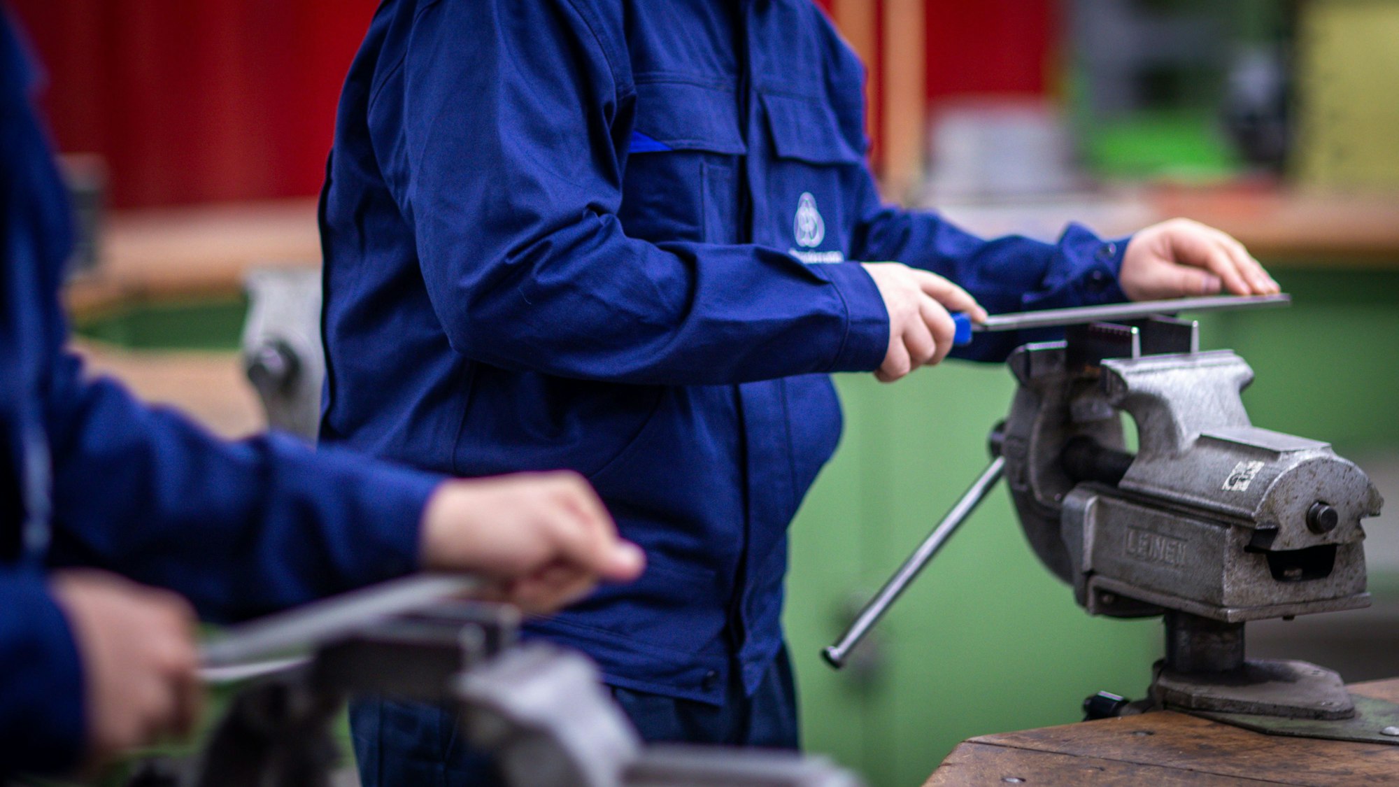 Zwei junge Leute feilen Metallstücke am Schraubstock.