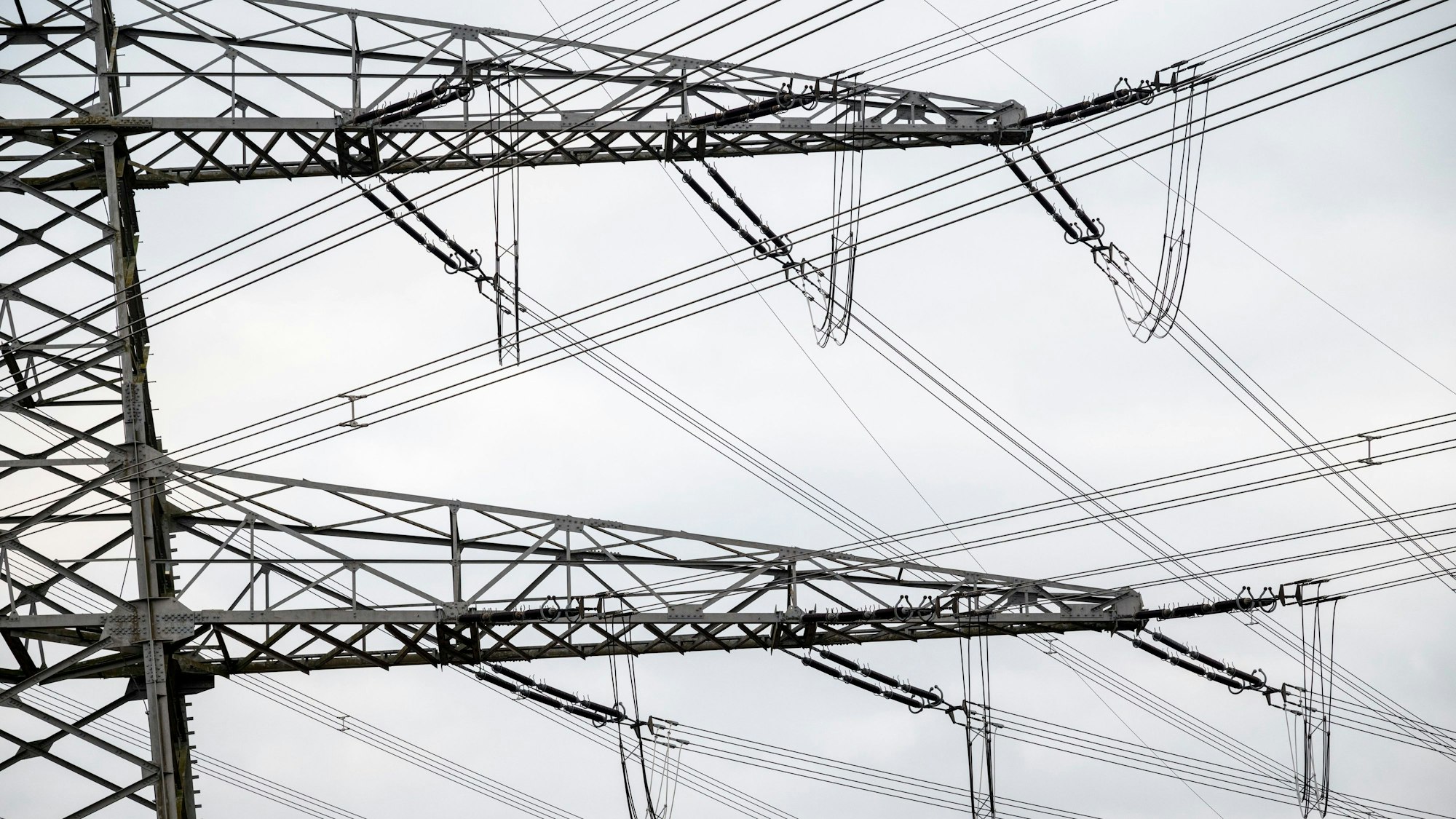 Ein Strommast steht neben einem Umspannwerk.