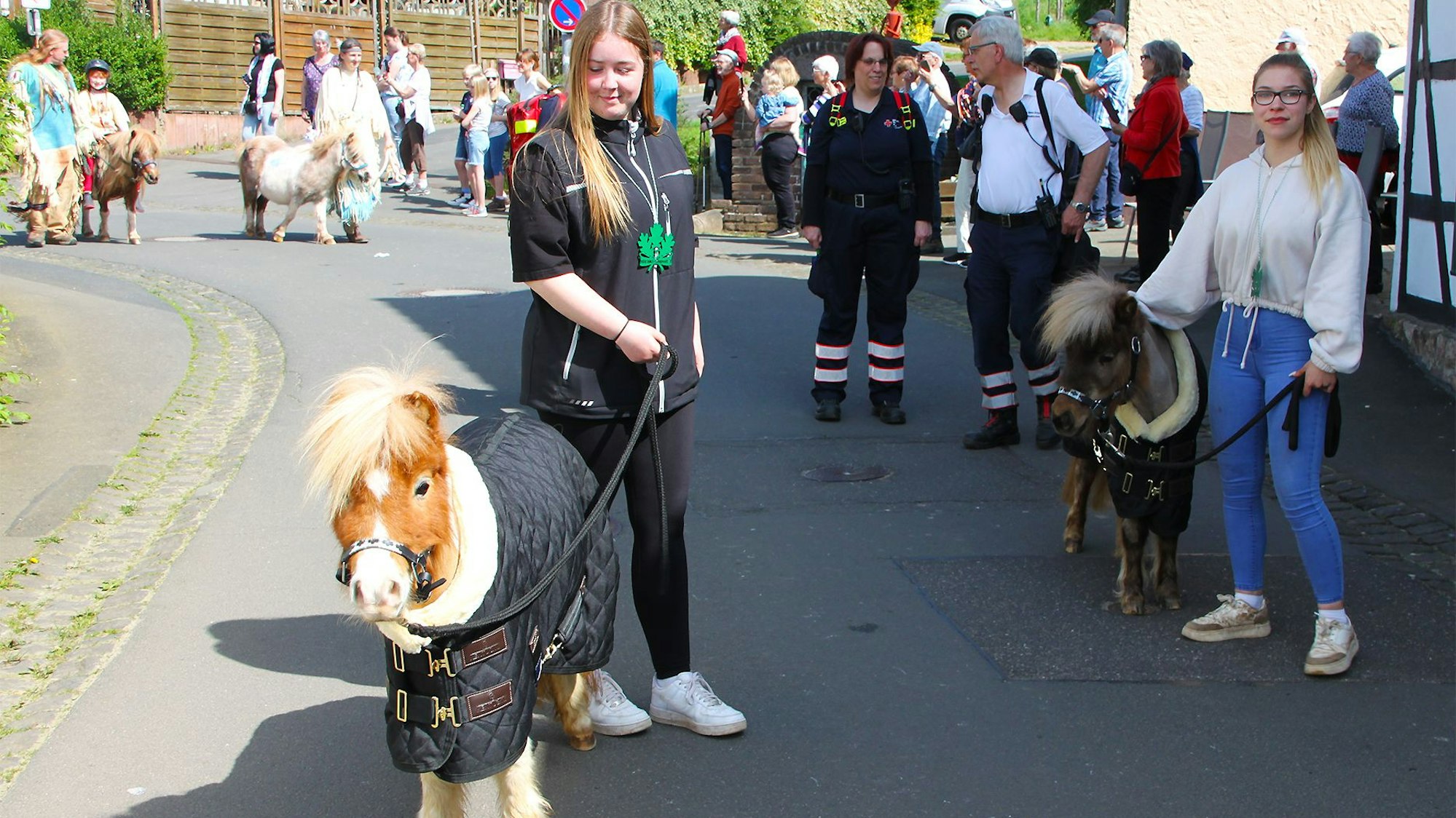 Die beiden jungen Teilnehmerinnen führen Ponys am Zügel, die kaum größer sind als ein großer Hund.