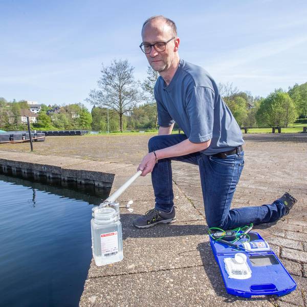 Das Foto zeigt einen Mann, der aus einer Talsperre eine Wasserprobe entnimmt.