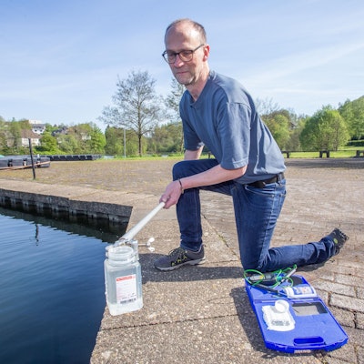 Das Foto zeigt einen Mann, der aus einer Talsperre eine Wasserprobe entnimmt.