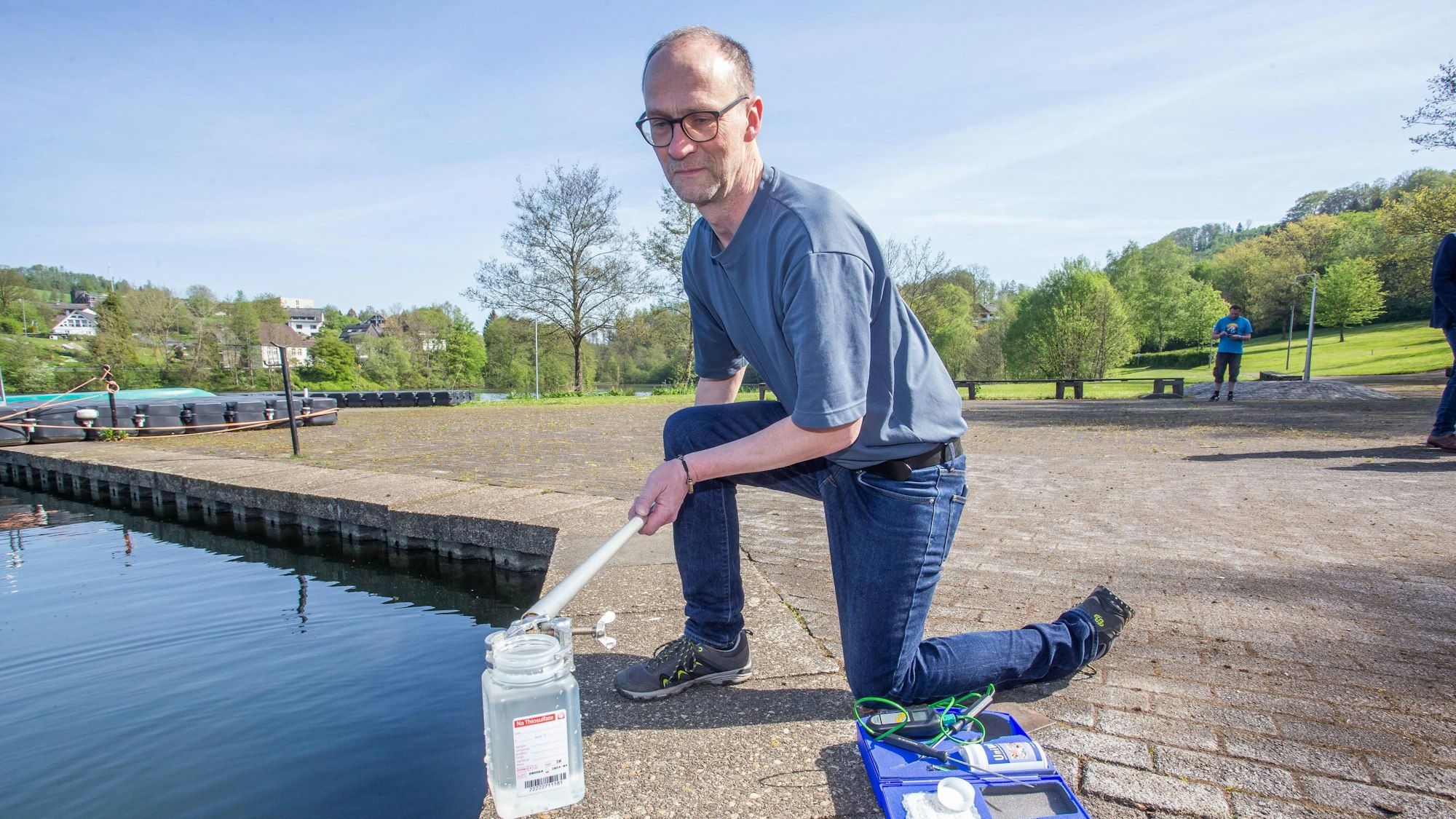 Das Foto zeigt einen Mann, der aus einer Talsperre eine Wasserprobe entnimmt.
