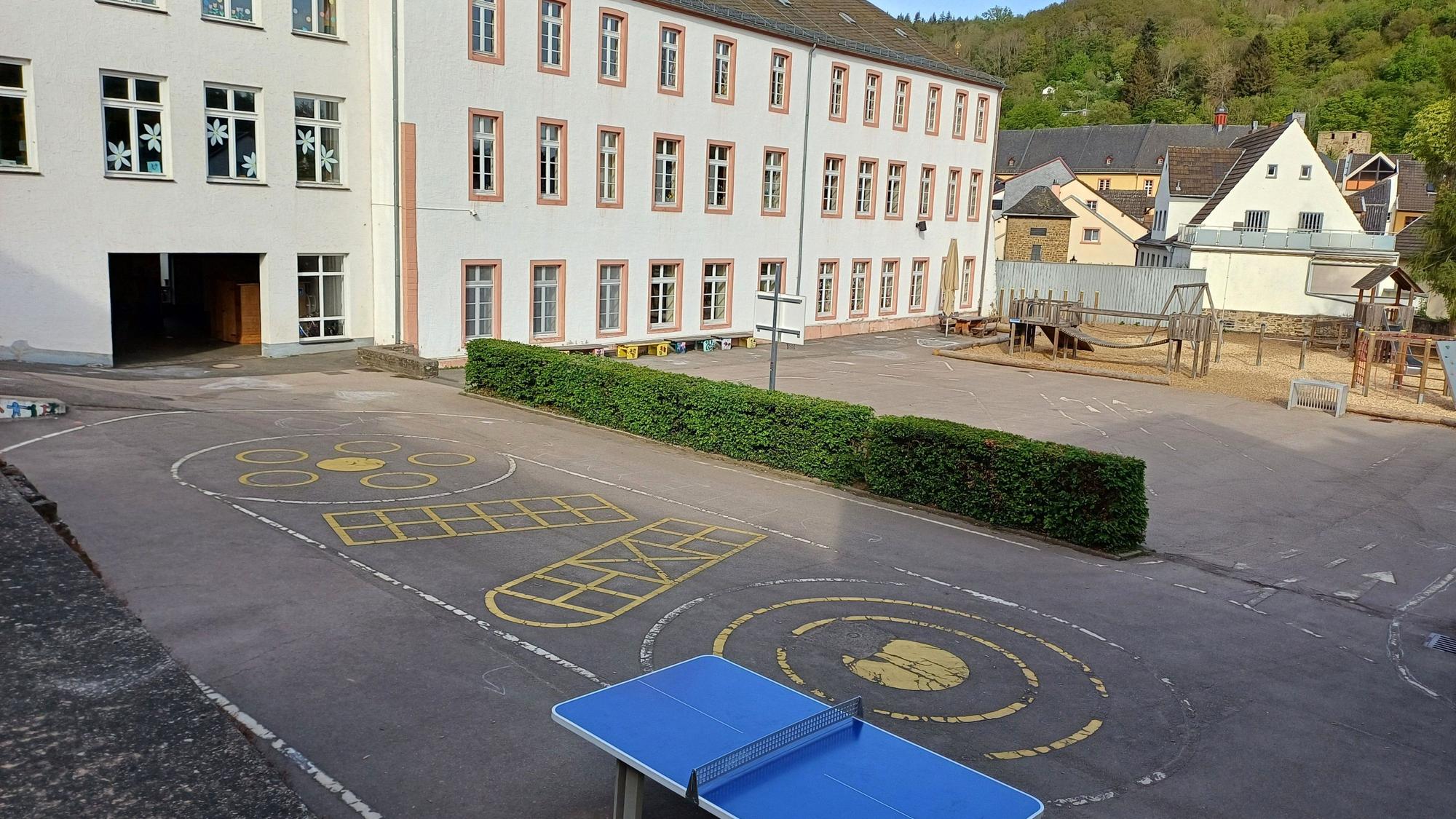 Das Bild zeigt den Blick auf die Grundschule mit dem Schulhof im Vordergrund.