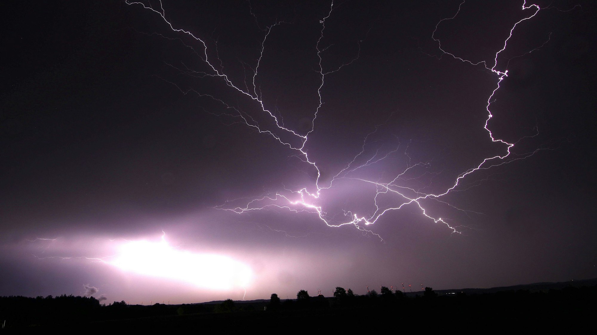 Ein Blitz zuckt bei einem Gewitter am nächtlichen Himmel.
