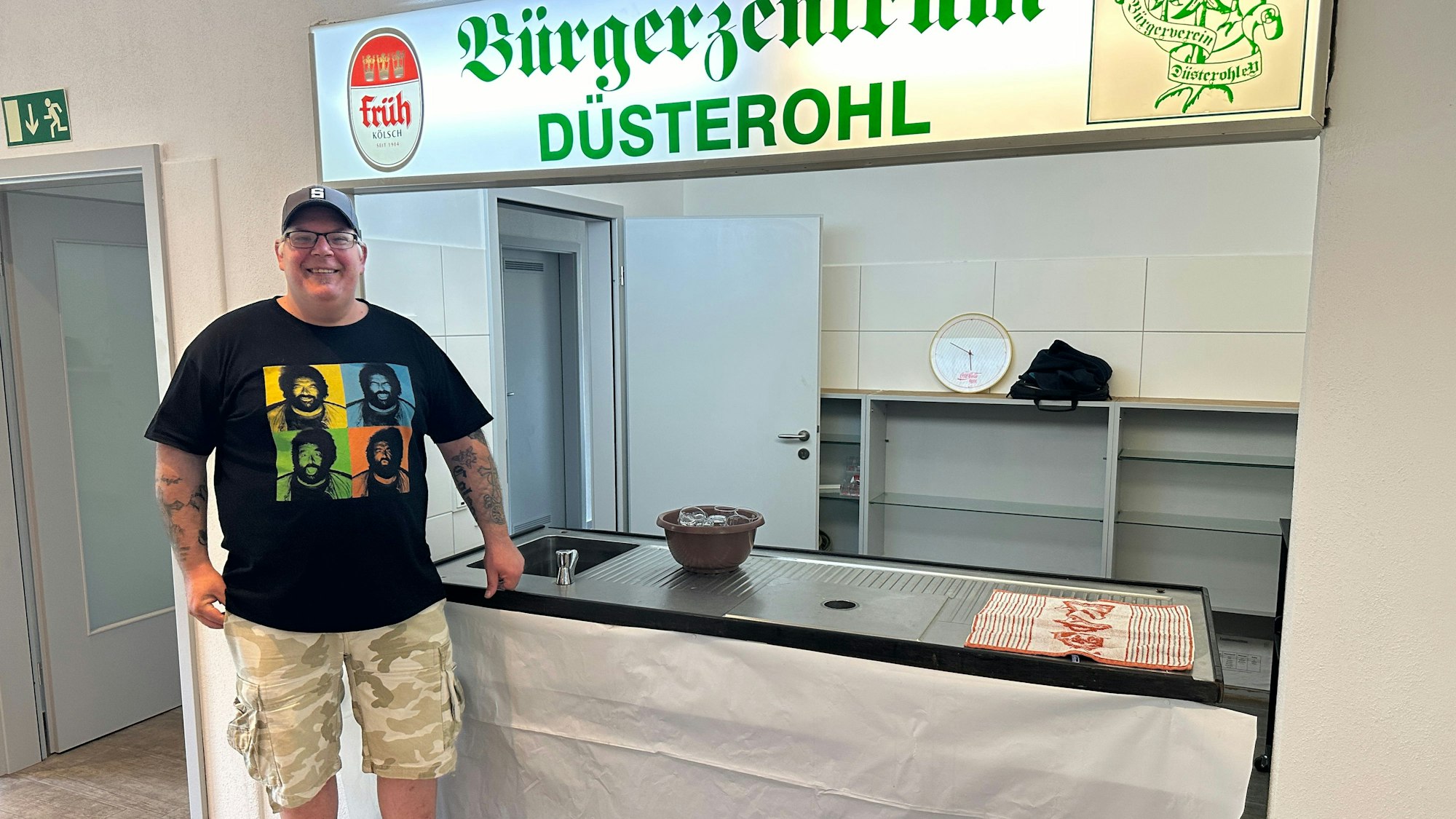 Sascha Scheider vom Bürgerverein Düsterohl steht vor einer niedrigen Theke, darüber hängt eine Leuchtreklame.