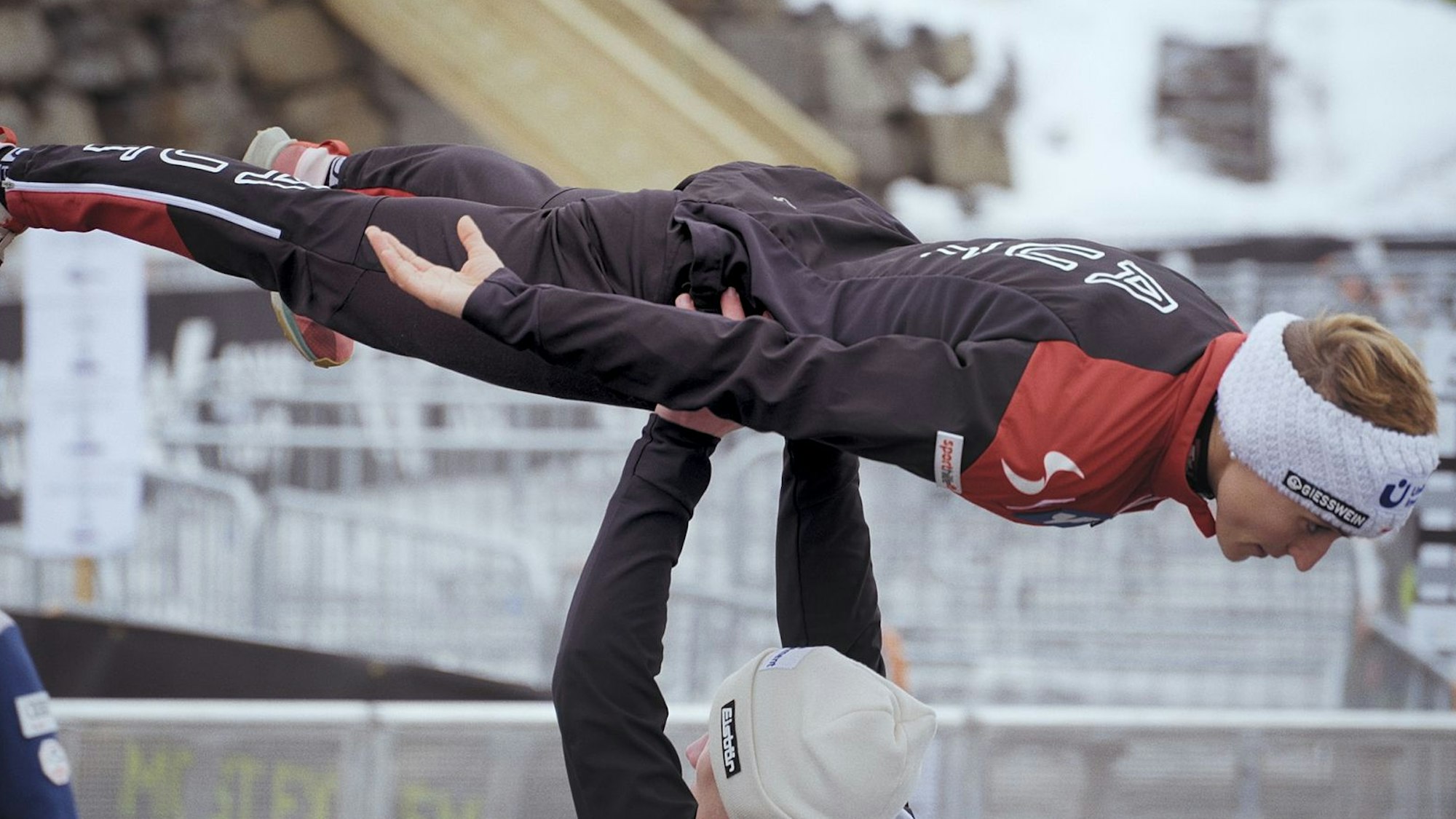 Eva Pinkelnig wird von einer Person auf den Händen in die Luft gehoben.