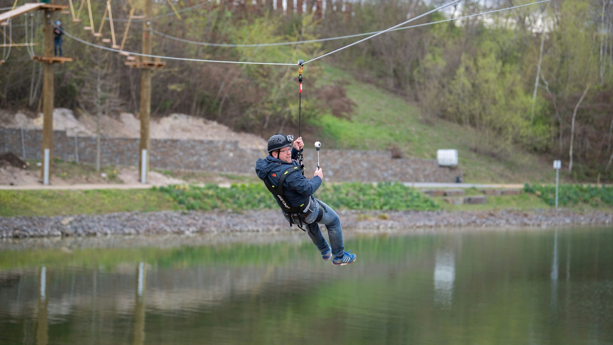 Ein Mann saust am Flying-Fox im Seepark über dem Wassersportsee entlang.