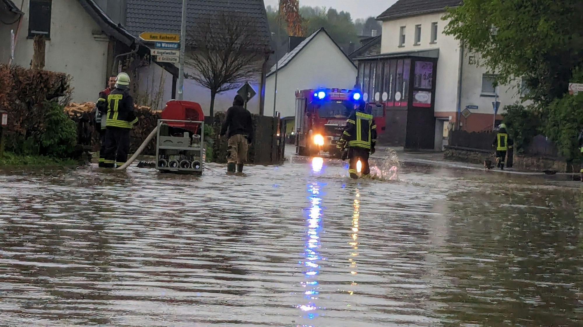 Das Bild zeigt eine überflutete Straße in Schmidtheim. Die Feuerwehr pumpt das Wasser ab.