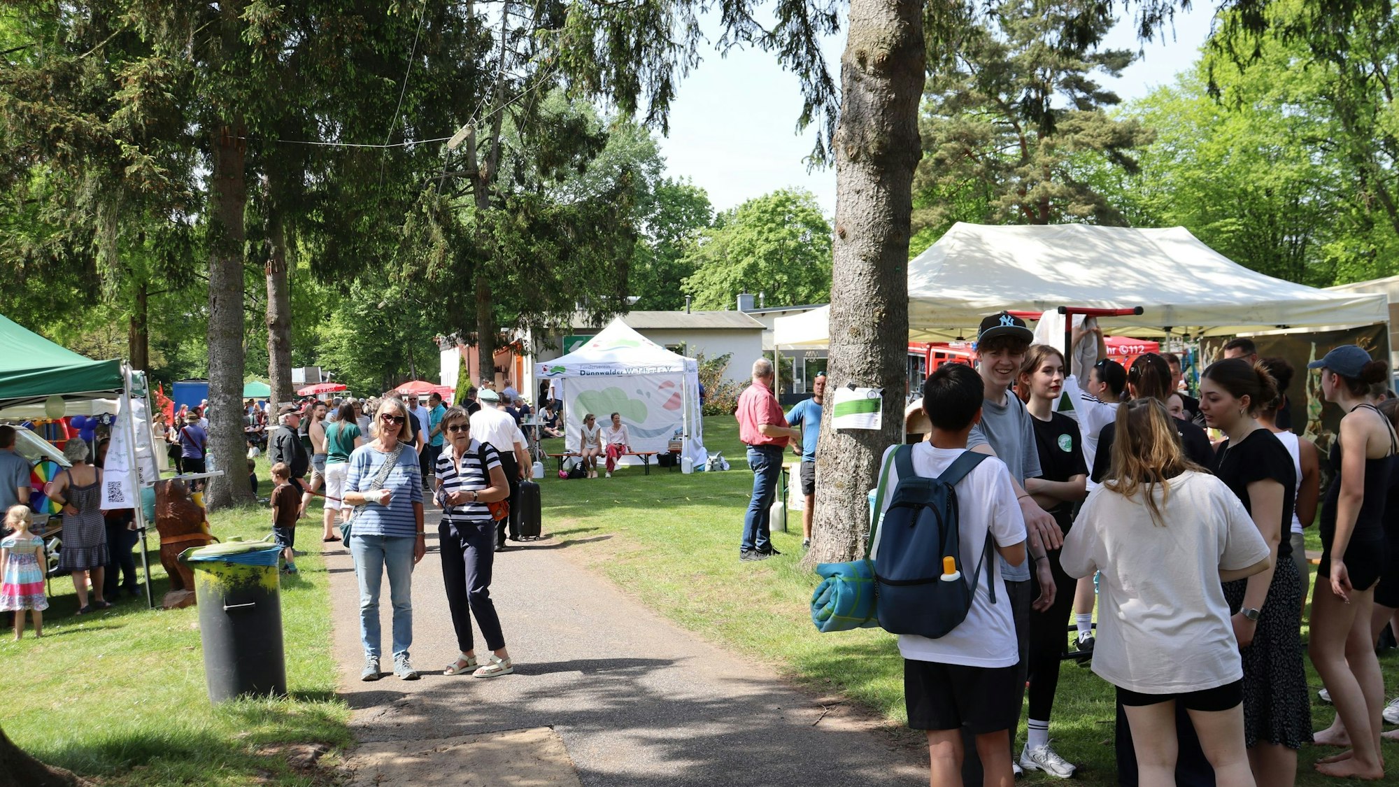 Besucher sehen sich bei sonnigem Wetter auf dem Maifest im Waldbad Dünnwald um. Foto von Uwe Schäfer.