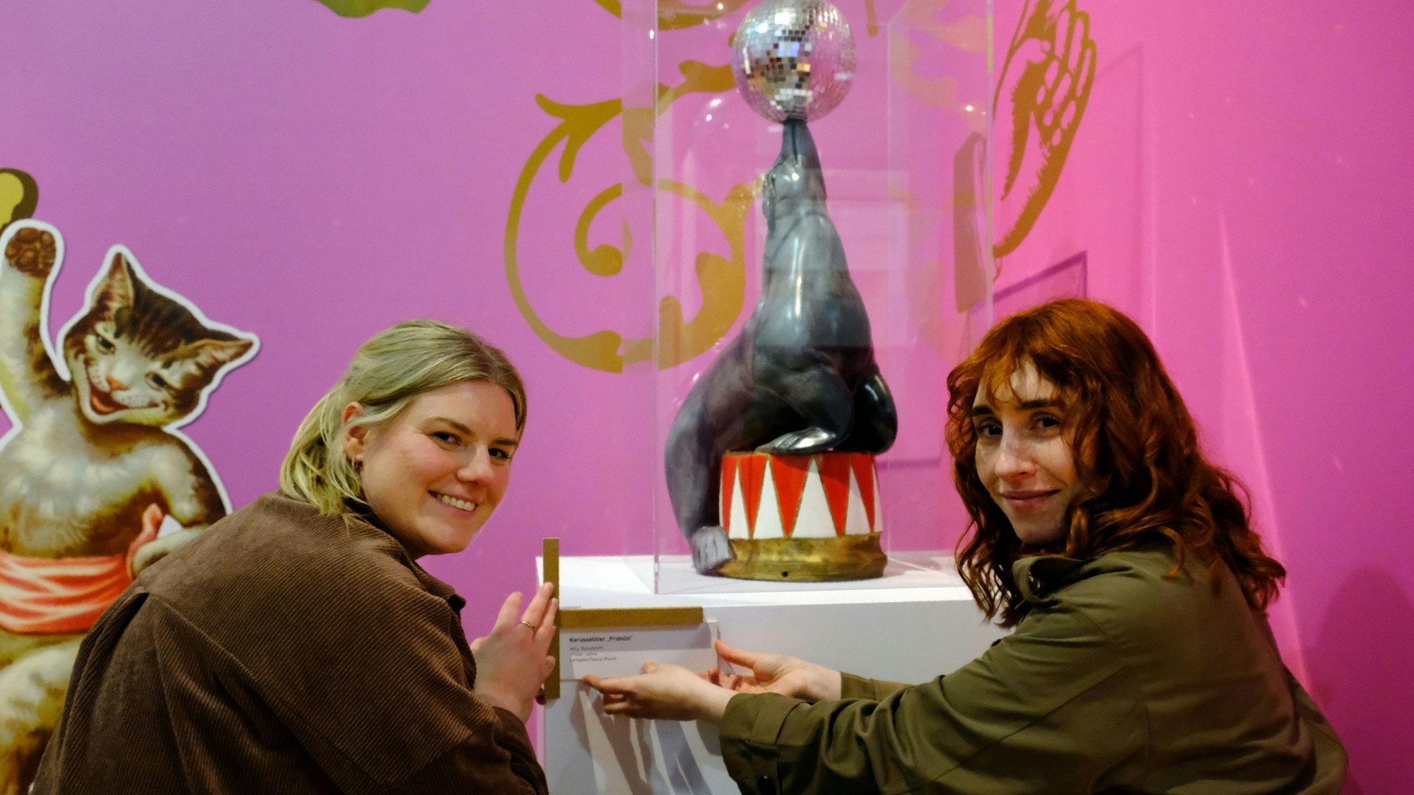 Kuratorin Ann Heinen (l.) und Alina Hilbrecht bringen die Beschriftung an einem Ausstellungsexponat an.