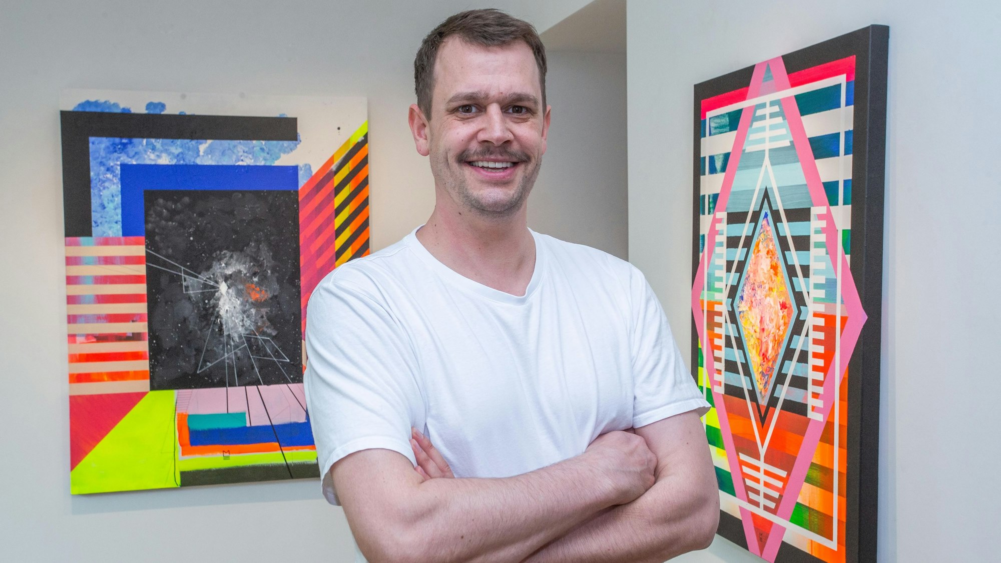 Das Foto zeigt den Künstler Michael Erbach und einige seiner Bilder.