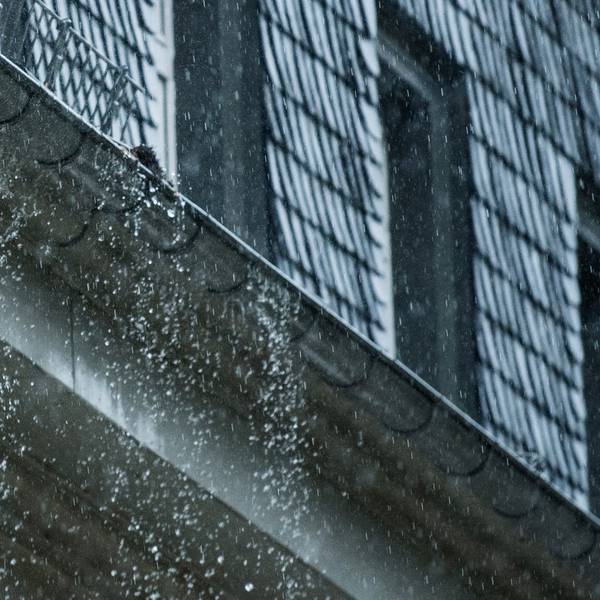 Viel Wasser fällt aus einer Regenrinne an einem Haus