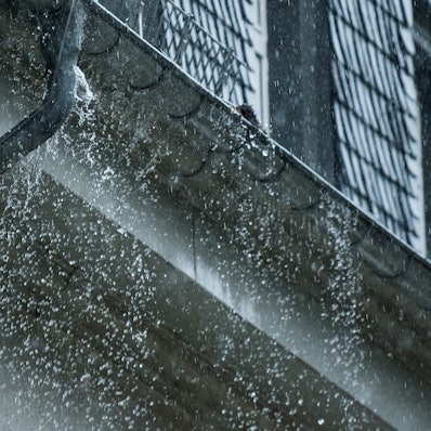 Viel Wasser fällt aus einer Regenrinne an einem Haus