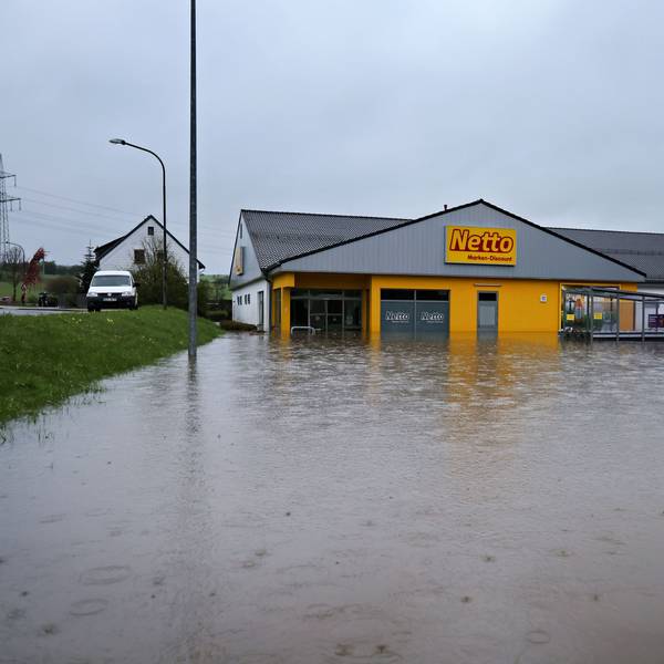 Das Bild zeigt den Netto-Markt von außen. Von vorne und von der rechten Seite ist er von Wasser umgeben.