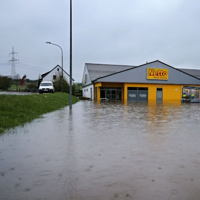 Das Bild zeigt den Netto-Markt von außen. Von vorne und von der rechten Seite ist er von Wasser umgeben.
