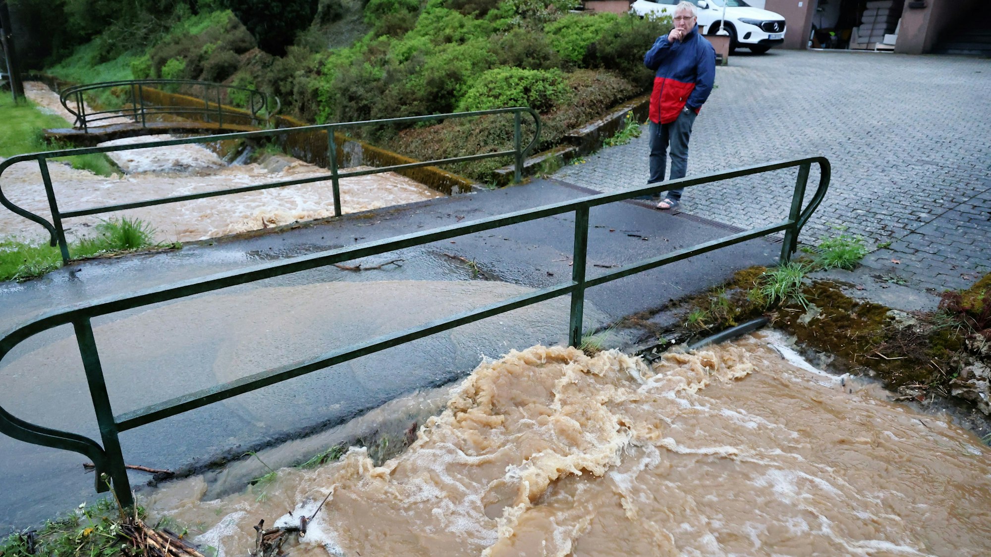 Ein Anwohner beobachtet, wie sich das schäumende Wasser an einer Brücke staut.