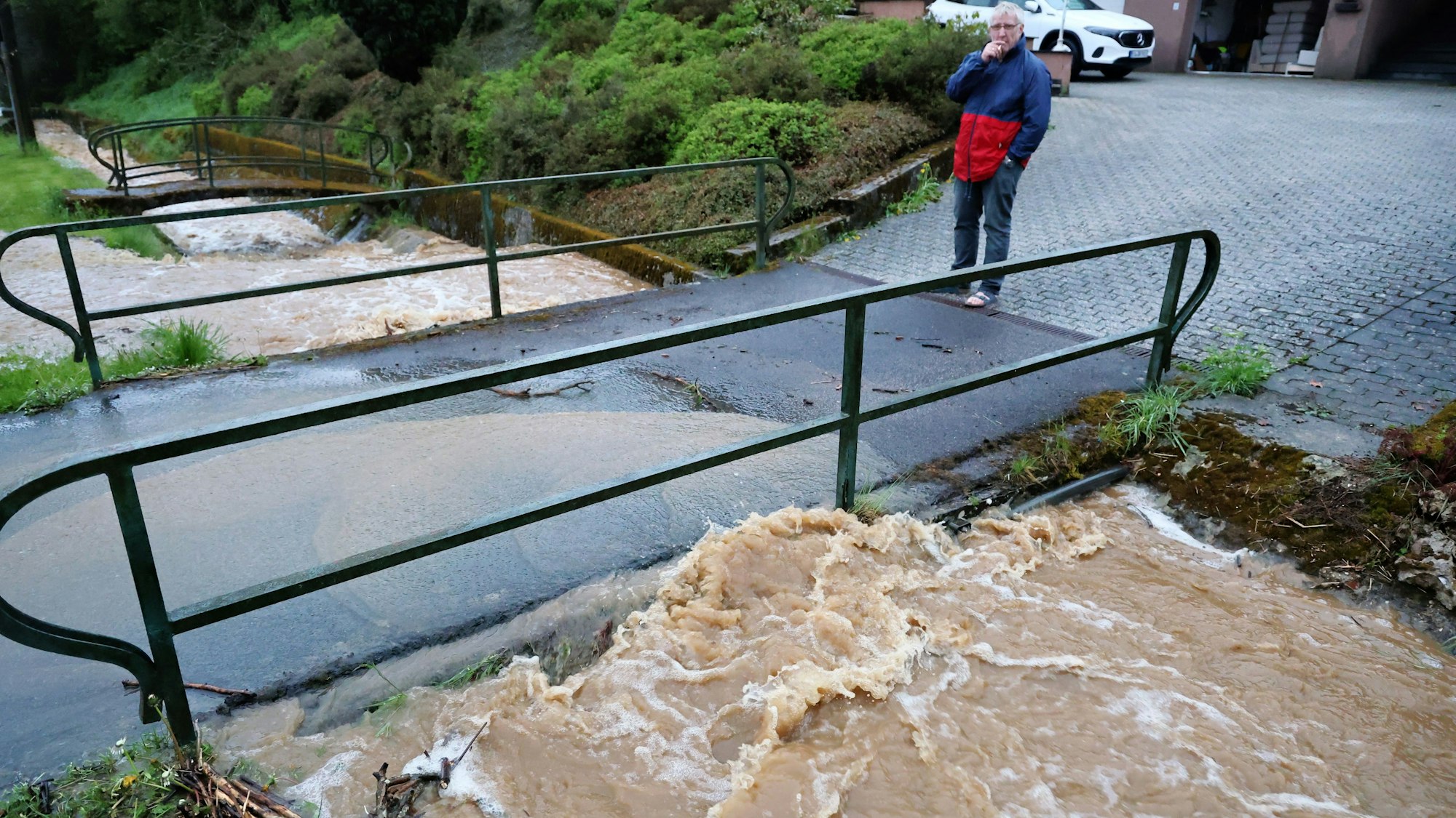 Ein Anwohner beobachtet, wie sich das schäumende Wasser an einer Brücke staut.