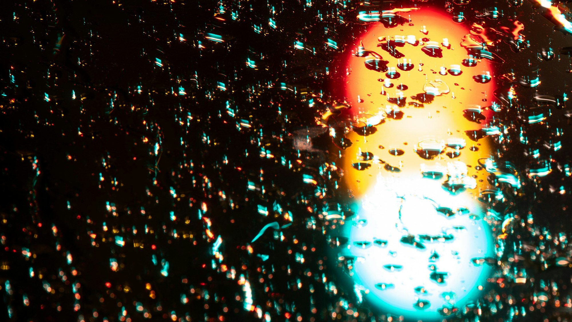 Eine Ampel leuchtet in allen Phasen Rot, Gelb und Grün. (Langzeitbelichtung)