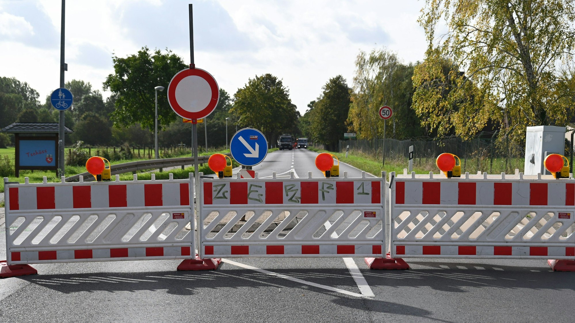 Absperrbaken blockieren die Durchfahrt auf einer Landesstraße.