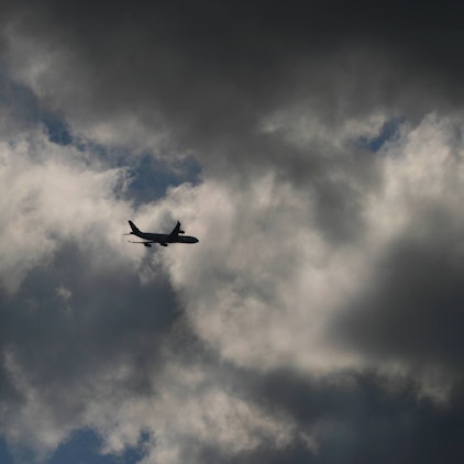 Ein Flugzeug fliegt inmitten eines Unwetters am Himmel in mehrere Gewitterwolken hinein. (Symbolbild)