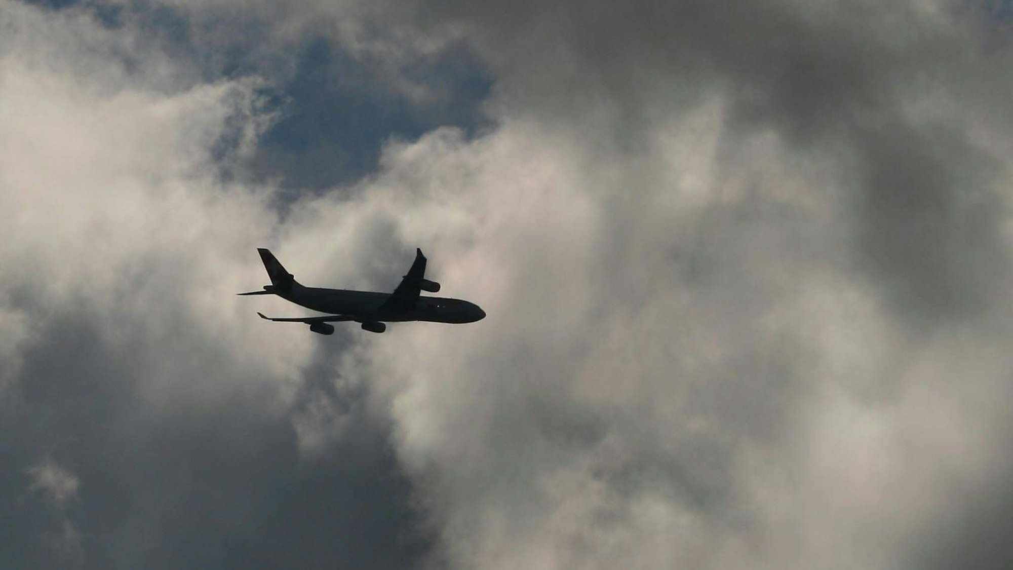 Ein Flugzeug fliegt inmitten eines Unwetters am Himmel in mehrere Gewitterwolken hinein. (Symbolbild)